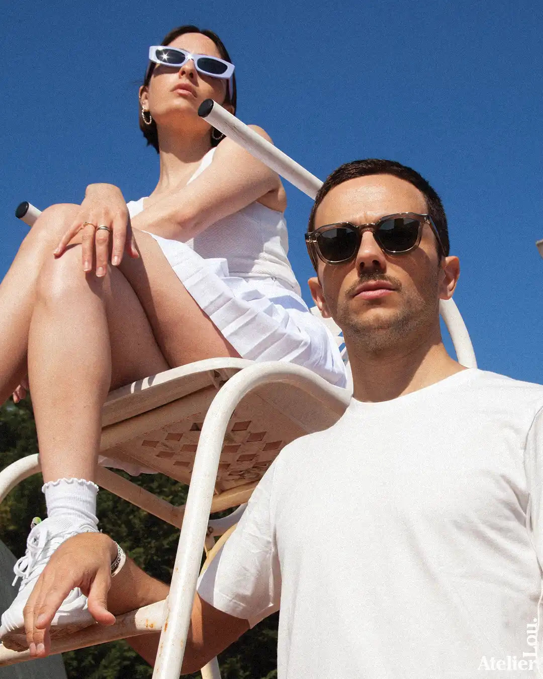 Deux personnes portant des lunettes de soleil et des vêtements blancs.