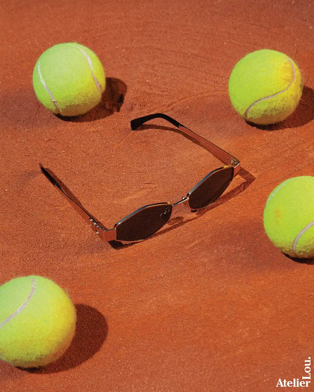 Lunettes de soleil sleek avec cadre en bronze et lentilles ovales foncées.