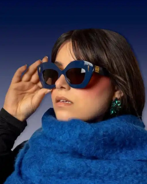 Femme portant des lunettes de soleil œil de chat bleu foncé et une écharpe bleue duveteuse.